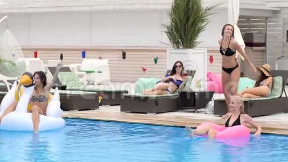 穿着泳衣的夏日派对女孩在背景人群中跳入蓝色泳池视频的预览图
