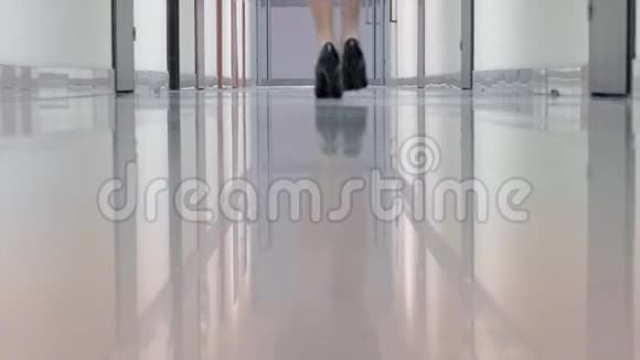 穿着黑色高跟鞋的女人走在办公楼的走廊里视频的预览图