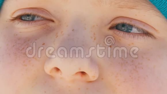 一个年轻的男孩有着一双不寻常的绿松石眼睛脸上长着雀斑戴着一顶蓝色的帽子紧紧地看着一边视频的预览图