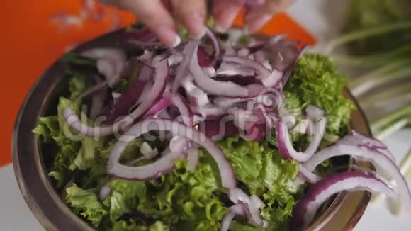女人在一个碗里倒紫色的洋葱和蔬菜沙拉视频的预览图