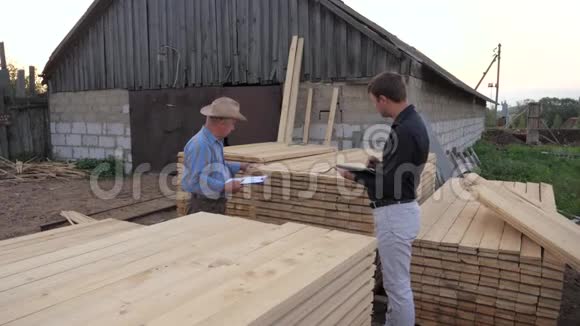 工人和商人在锯木厂检查计数访问包木板视频的预览图