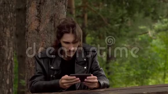 他坐在树林里拿着电话视频的预览图