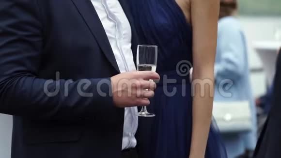 年轻人拿着一杯香槟在派对上拥抱着穿着蓝色裙子的女人视频的预览图