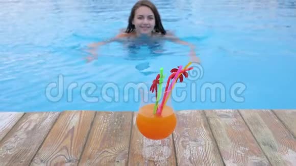 在泳池边度假的女孩穿比基尼的快乐年轻女人在泳池的蓝色水中喝着生动的鸡尾酒视频的预览图