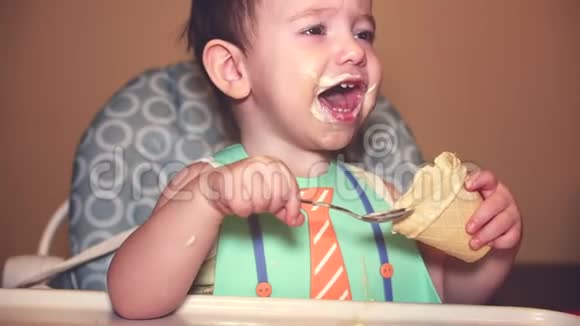 婴儿在胸前吃冰淇淋在华夫饼杯看着相机要求更多的冰淇淋脸上的视频的预览图