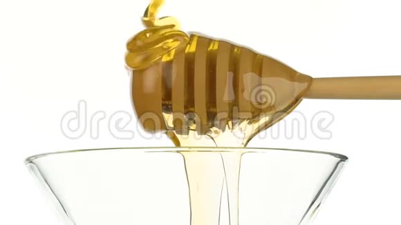 玻璃碗倒入蜂蜜和木棍蘸白色背景视频的预览图