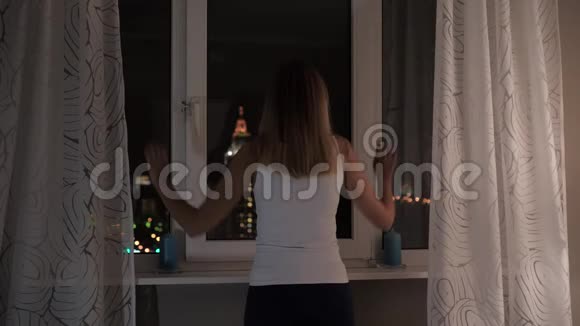 女人站在窗前夜看街灯窗帘视频的预览图