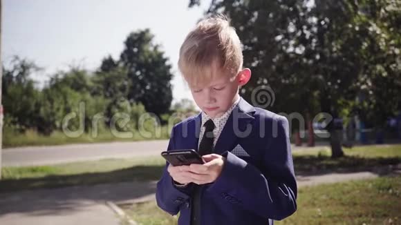 穿西装的小男孩拿着智能手机在街上玩游戏视频的预览图