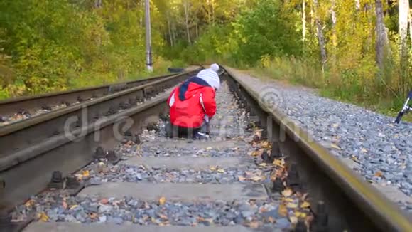 孤独的男孩在铁轨上玩耍危险的游戏和娱乐活动秋天温暖的一天视频的预览图
