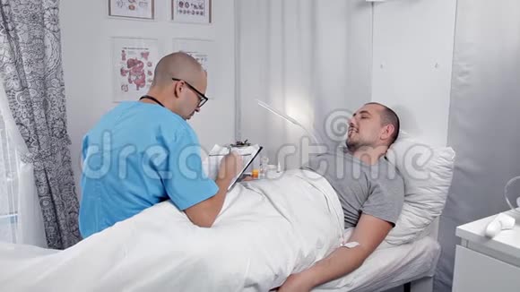 年轻男性病人在急诊室咨询医生检查病人并在笔记本上做笔记视频的预览图