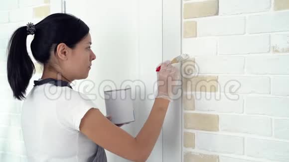 女工人在公寓或房子里用刷子粉刷墙壁建筑修理和翻新视频的预览图