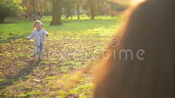 快乐的家庭一起度过公园里的自由时光小可爱有两条马尾辫的小女孩正在向年轻的母亲跑去视频的预览图