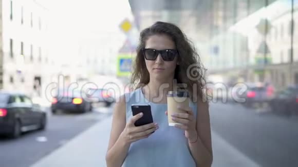 戴墨镜的漂亮女人在夏天的大街上发短信喝咖啡视频的预览图