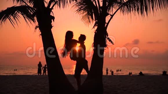 剪影情侣在夕阳下亲吻背景是惊人的热带自然视频的预览图