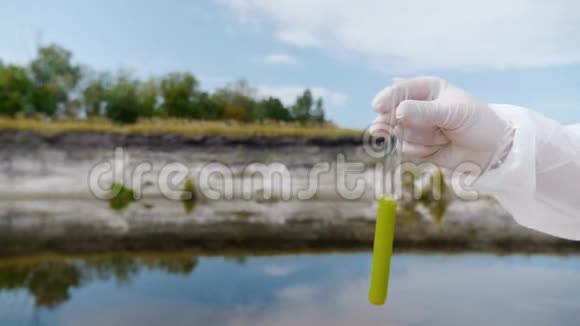 穿着防护服的人的手显示了一个试管其中分析了来自污染河流或湖泊的水视频的预览图