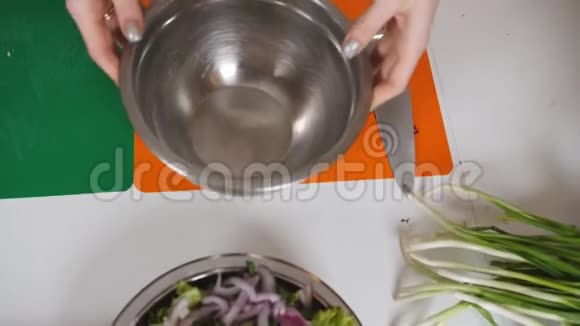那个女人把沙拉倒在碗里厨房蔬菜沙拉的准备视频的预览图