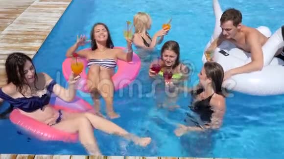 暑假朋友们在充气环上游泳到游泳池里喝彩色饮料视频的预览图