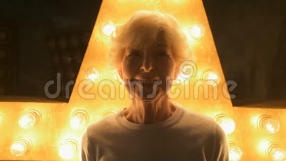年长的微笑的女人站在灯光下视频的预览图