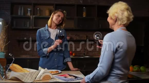 快乐迷人的女人和年迈的母亲在厨房喝酒视频的预览图
