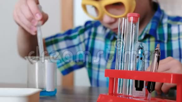 家庭化学实验男孩用吸管从烧杯中倒入蓝色液体到试管中视频的预览图