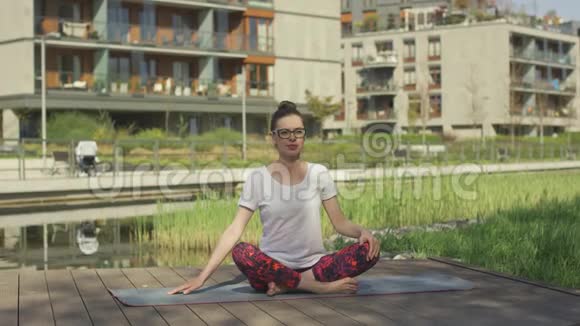 漂亮的年轻女子在家附近做瑜伽视频的预览图