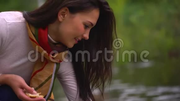 夏天美丽的年轻女子在湖边喂鸭子特写快乐的笑脸4千克视频的预览图