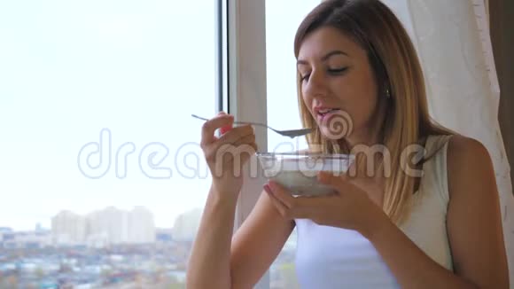 站在窗口看着外面吃着牛奶的女人视频的预览图