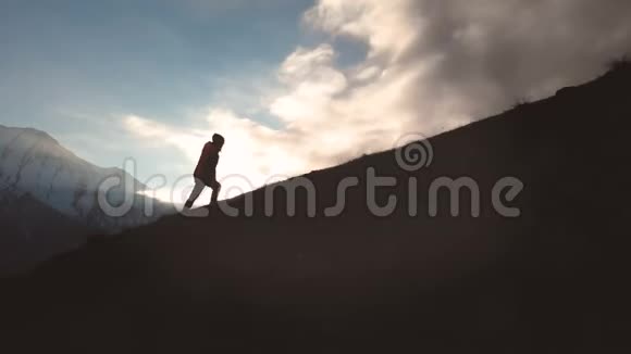 一个女孩在山的边缘行走的史诗般的空中景象就像一个美丽的轮廓视频的预览图