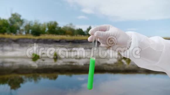 穿着防护服的人的手显示了一个试管其中分析了来自污染河流或湖泊的水视频的预览图