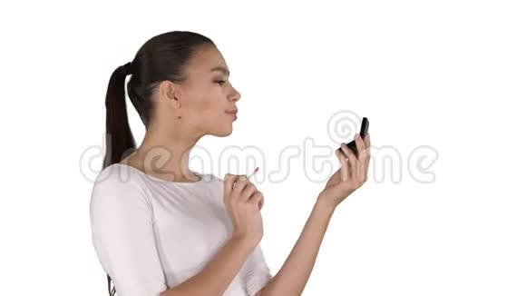 漂亮的年轻女人在白色背景上涂口红视频的预览图