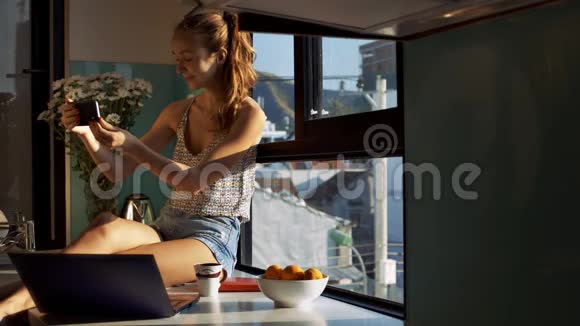 年轻女子在整洁的厨房里用笔记本电脑自拍视频的预览图