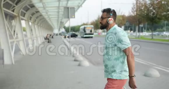 戴着耳机的非洲男人正走到机场拉着他的行李准备好度假了4K录像视频的预览图