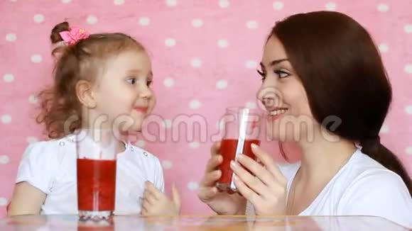 母女俩正喝着冰沙笑眯眯的年轻的女人和她的孩子一起享受一杯清爽可口的饮料粉色视频的预览图
