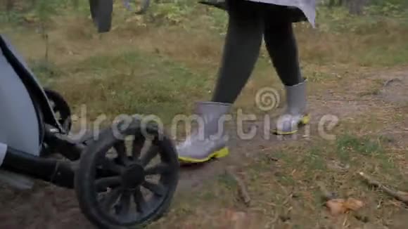 妈妈带着婴儿车穿过树林车轮和腿的特写视频的预览图