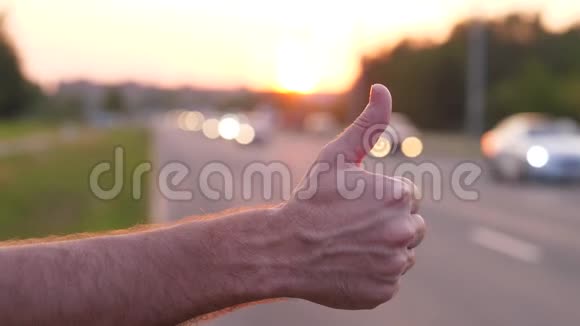 男子手举起大拇指在路上搭便车的人试图抓住汽车视频的预览图