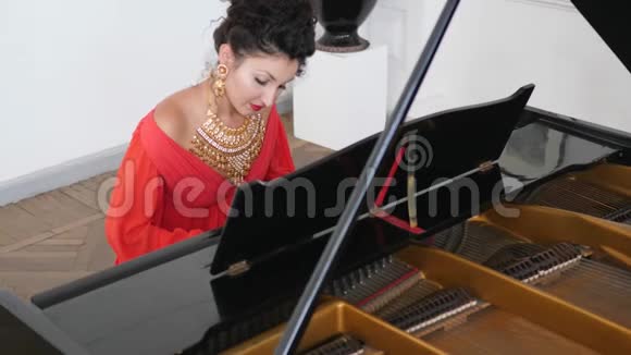优雅的年轻女子穿着别致的珠宝慢动作演奏钢琴视频的预览图