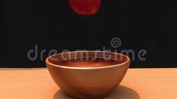 红苹果掉进木碗里的水里视频的预览图