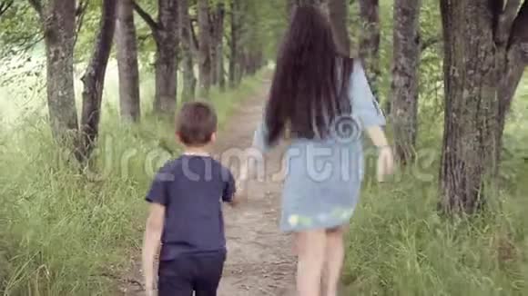 可爱快乐的小女孩和男孩在森林里奔跑双手微笑兄弟姐妹散步视频的预览图