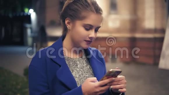 年轻迷人的女人晚上在城里用智能手机漂亮的女孩在户外的智能手机上发短信旅游女孩视频的预览图