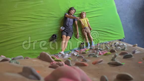 一个年轻的攀岩教练教小男孩如何在一个巨石攀岩馆里爬墙视频的预览图