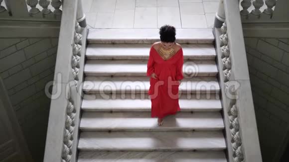 俯视图上穿着别致红色长裙的女子高跟鞋走下一个大楼梯视频的预览图
