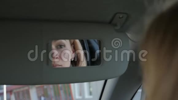 年轻迷人的女人正在车里化妆看着后视镜慢动作视频的预览图