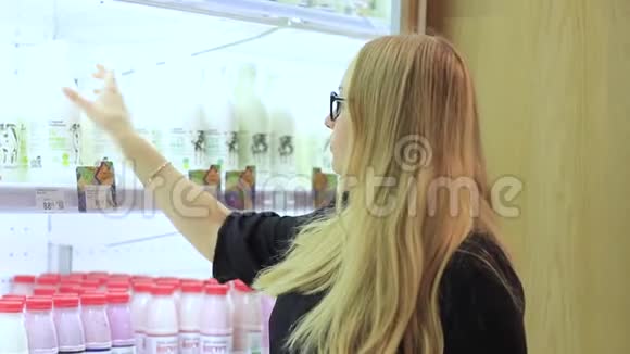 女孩正在考虑超市里放一瓶牛奶视频的预览图
