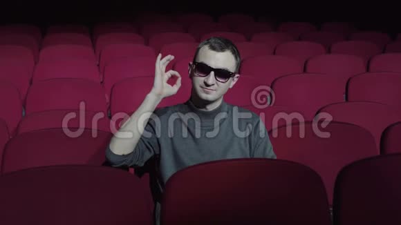 单人坐在黑色电影院里舒适的红色椅子上并显示OK标志视频的预览图