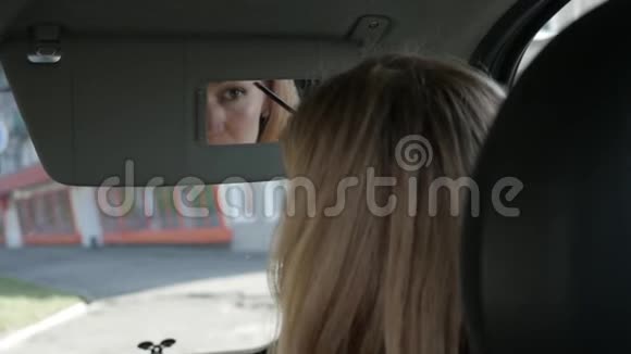 年轻迷人的女人在车里画眉毛看着后视镜慢动作视频的预览图