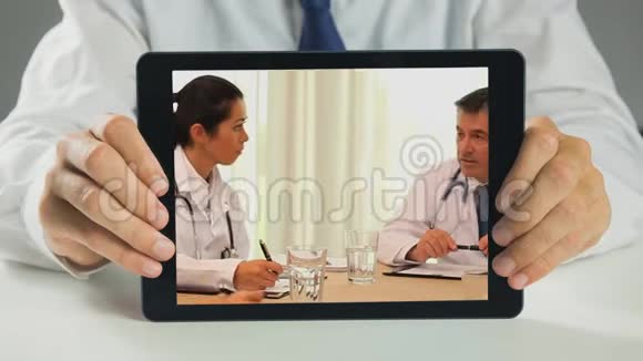 医生拿着数码平板电脑开会讨论视频的预览图