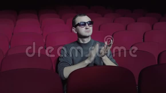 3着3D眼镜的帅哥坐在黑色电影院舒适的红色椅子上鼓掌视频的预览图