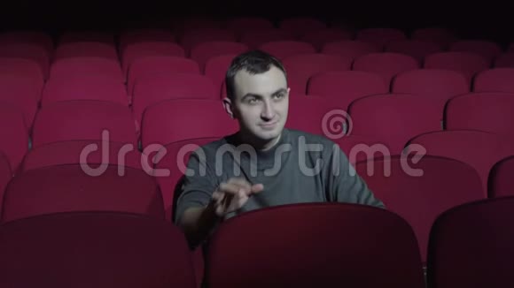 一个人坐在舒适的红色椅子上鼓掌离开黑暗的电影院视频的预览图