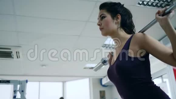 力量训练女子在运动综合体中用杠铃做运动视频的预览图
