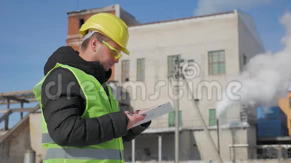 戴安全帽的工程师正在一家工业工厂使用平板电脑视频的预览图